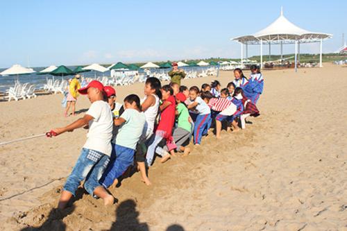 图为学生们在加勒比海盗水上乐园沙滩进行的拔河比赛