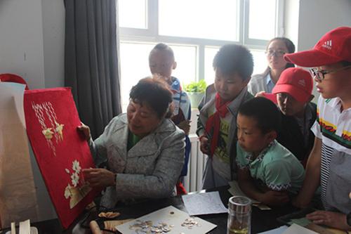 图为学生在博湖县非物质文化遗产传承中心观看绣花